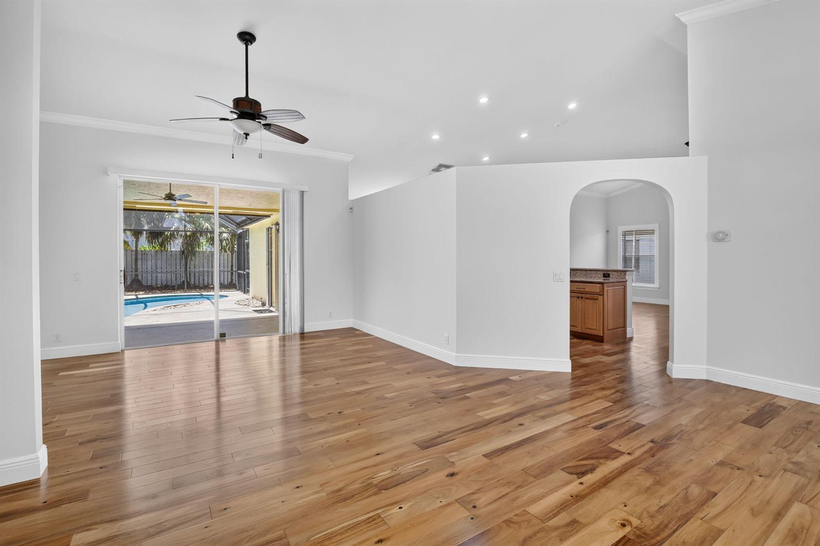 An empty living room with hardwood floors, a ceiling fan, and a sliding glass door — 1959 Water Ridge Dr, Weston FL 33326, WESTON, FL