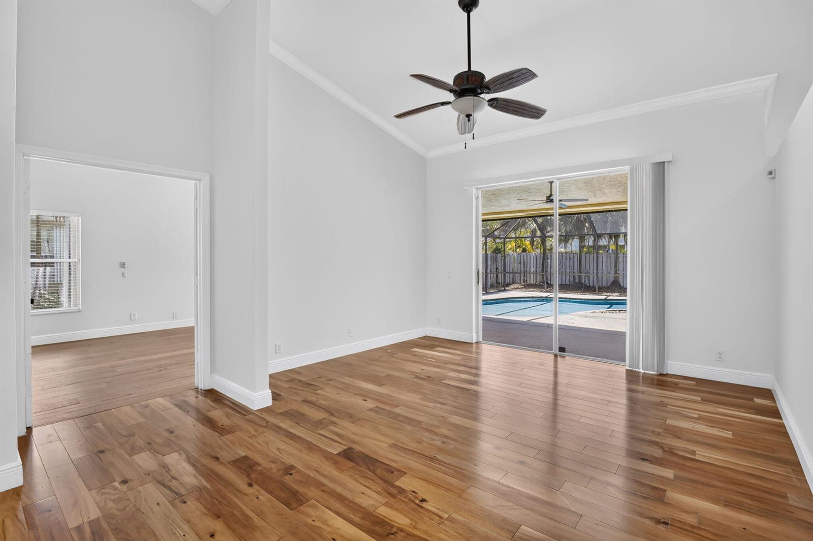 A living room with wood flooring, a ceiling fan, and sliding doors leading to a pool — 1959 Water Ridge Dr, Weston FL 33326, WESTON, FL