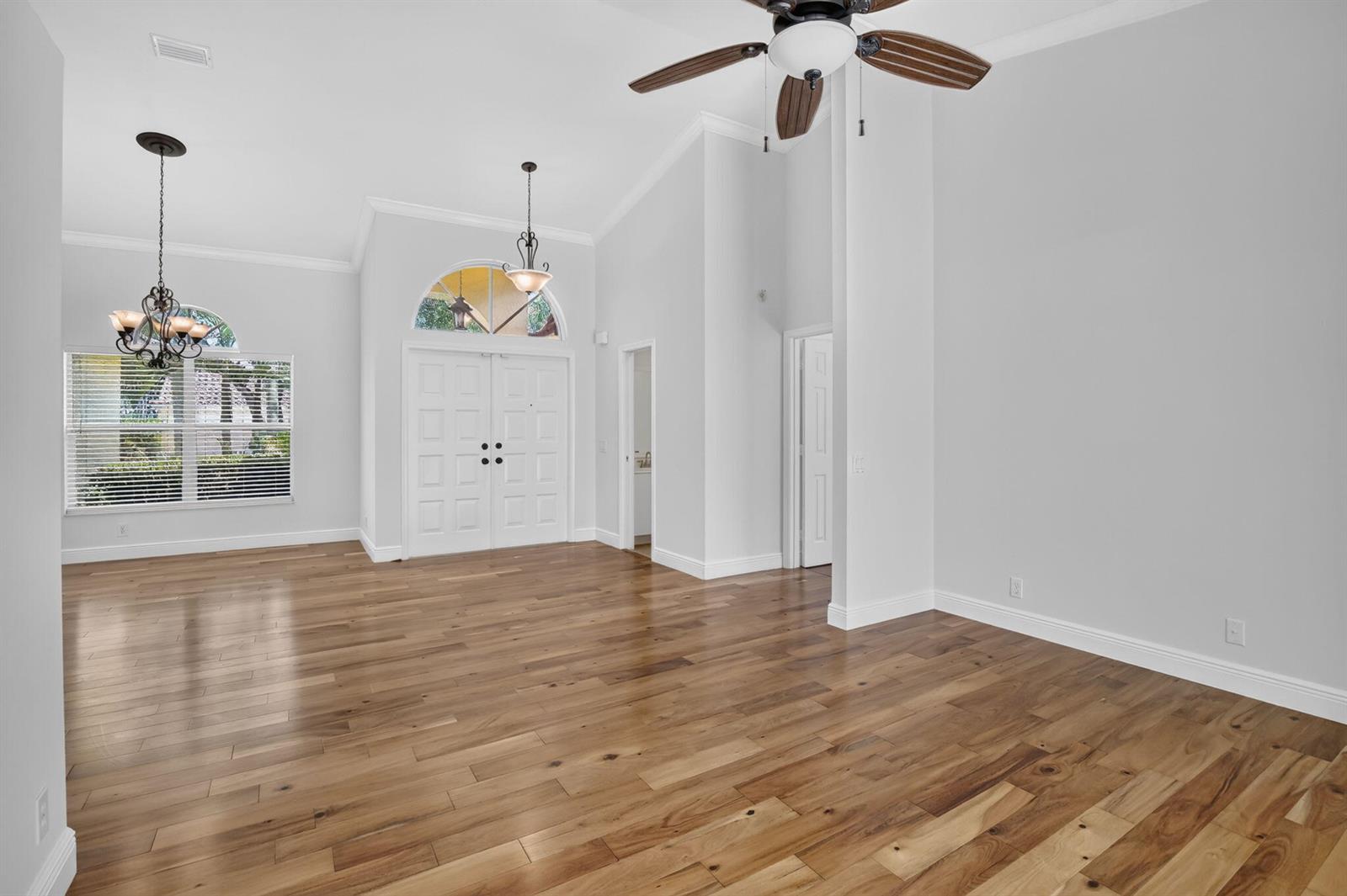 An empty room with hardwood floors, a vaulted ceiling, a ceiling fan, and double doors — 1959 Water Ridge Dr, Weston FL 33326, WESTON, FL