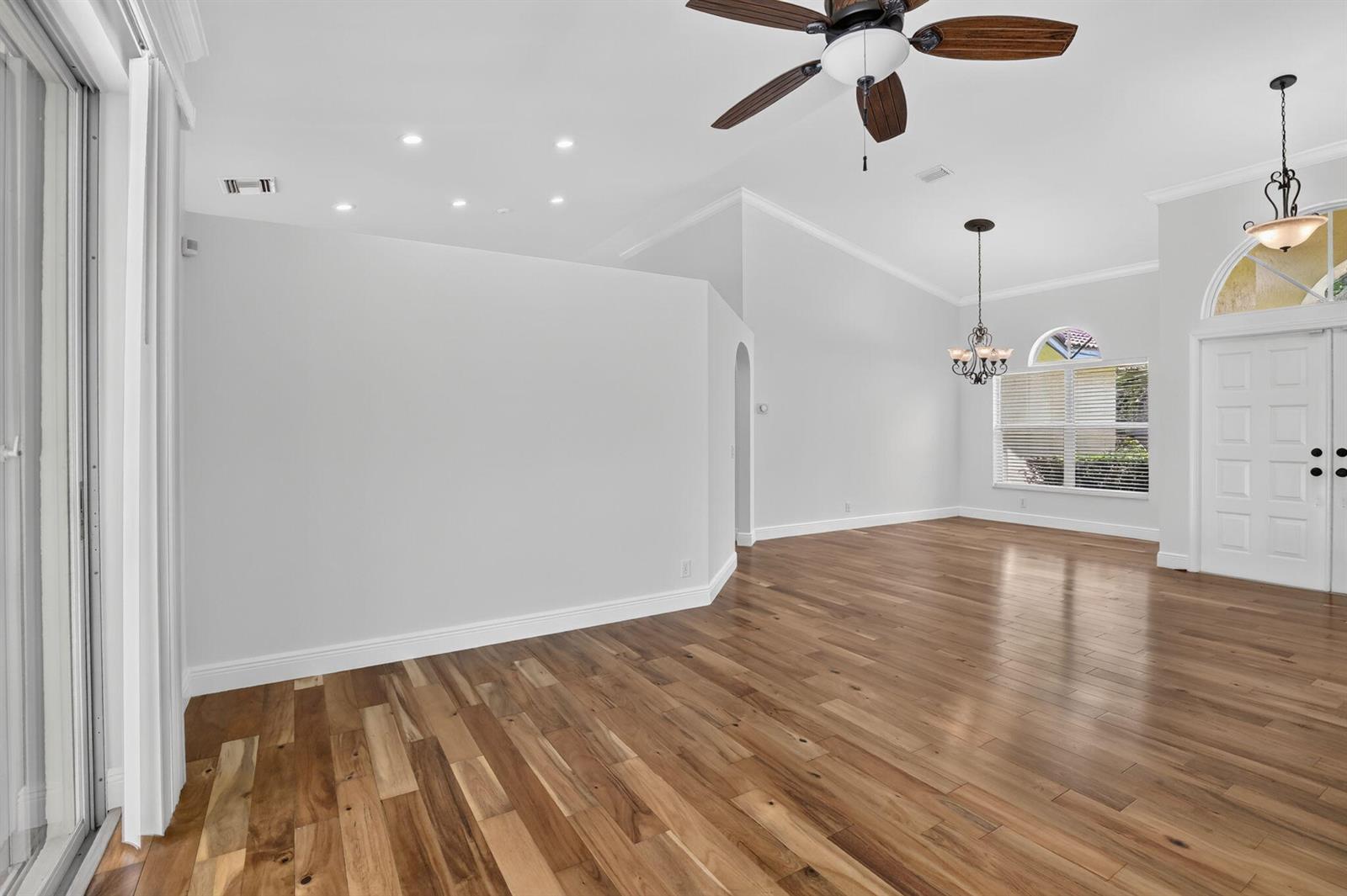 An empty room features hardwood floors, a ceiling fan, and a chandelier near the entrance — 1959 Water Ridge Dr, Weston FL 33326, WESTON, FL