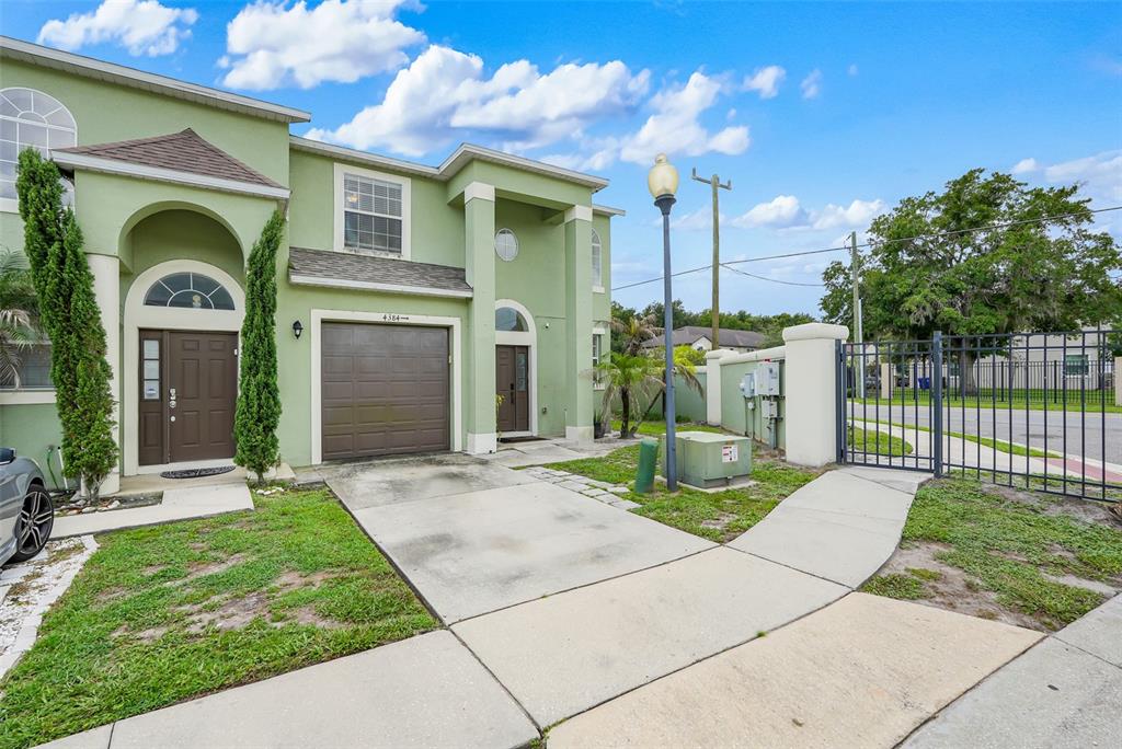 A two-story green townhouse features a brown garage door, a front entrance, and a driveway — 4384 PARADISE COVE COURT, KISSIMMEE, FL