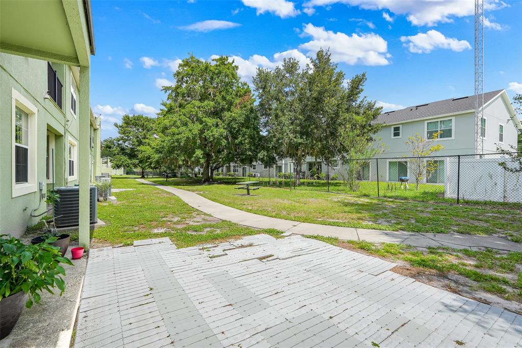 A view of a patio with a concrete walkway leading through a grassy courtyard area — 4384 PARADISE COVE COURT, KISSIMMEE, FL
