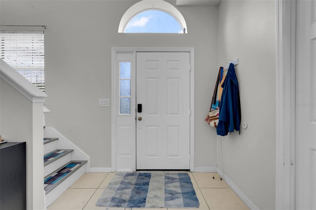 An entryway features a white front door, a tiled floor, and a staircase with patterned treads — 4384 PARADISE COVE COURT, KISSIMMEE, FL