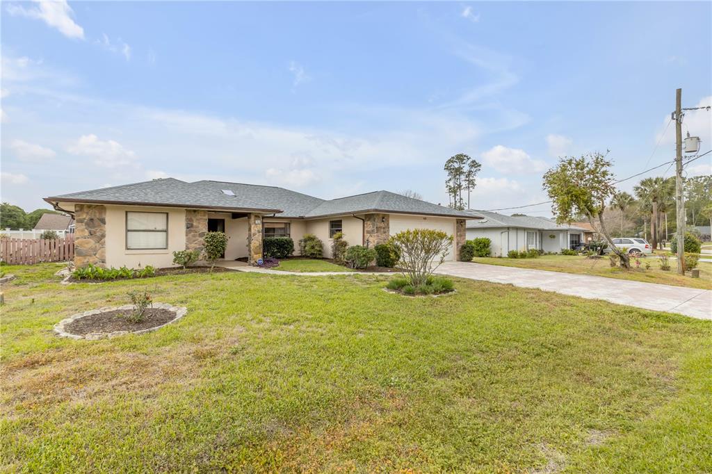A single-story house with a stone facade, a shingled roof, and a concrete driveway — 45 WEBSTER LANE, PALM COAST, FL