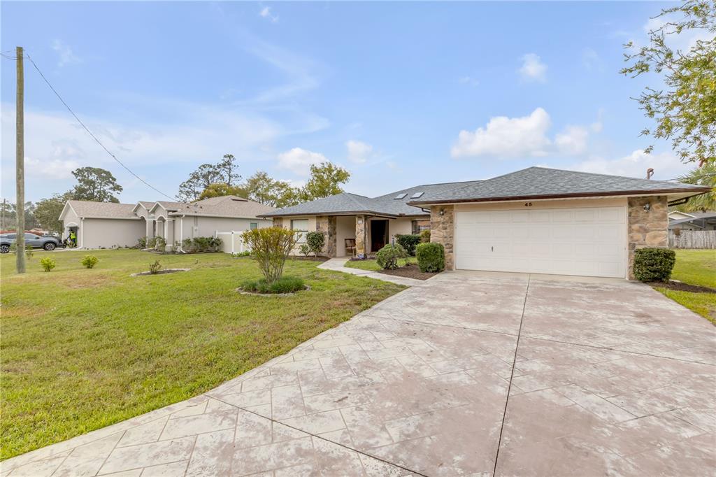 A single-story house with a stone facade, a two-car garage, and a stamped concrete driveway — 45 WEBSTER LANE, PALM COAST, FL