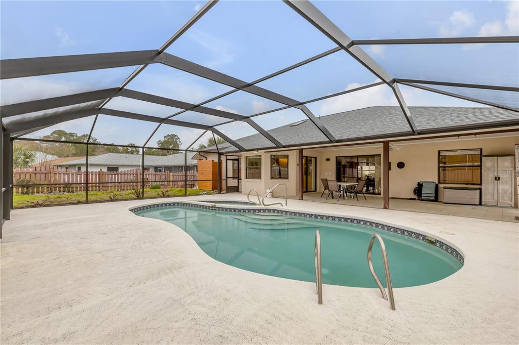 A screened-in patio features a swimming pool with an attached spa and concrete decking — 45 WEBSTER LANE, PALM COAST, FL