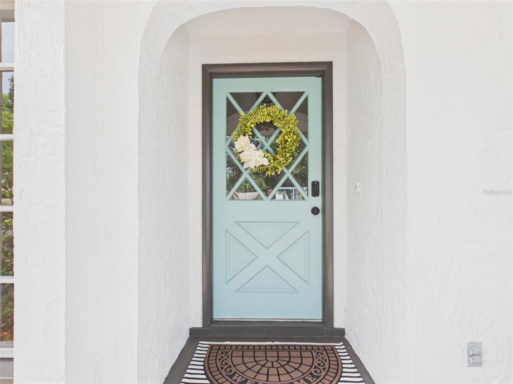 A light blue front door with a diamond-patterned glass insert sits within an arched entryway — 533 66TH STREET N, PALM HARBOR, FL