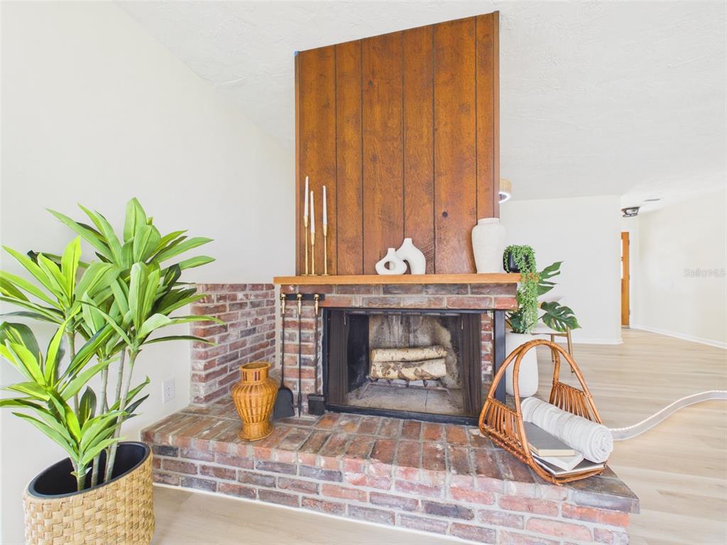 A brick fireplace features a wood-paneled accent wall and a wooden mantel in a room — 533 66TH STREET N, PALM HARBOR, FL