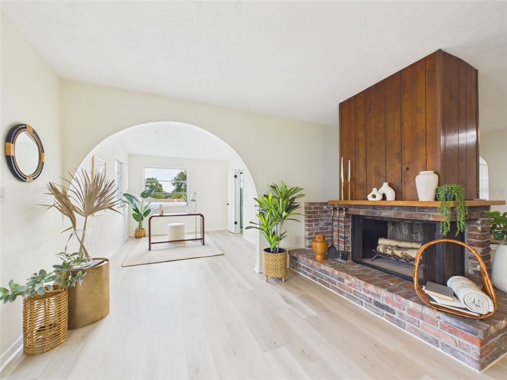 A living room features a brick fireplace with wood paneling and a large arched entryway — 533 66TH STREET N, PALM HARBOR, FL