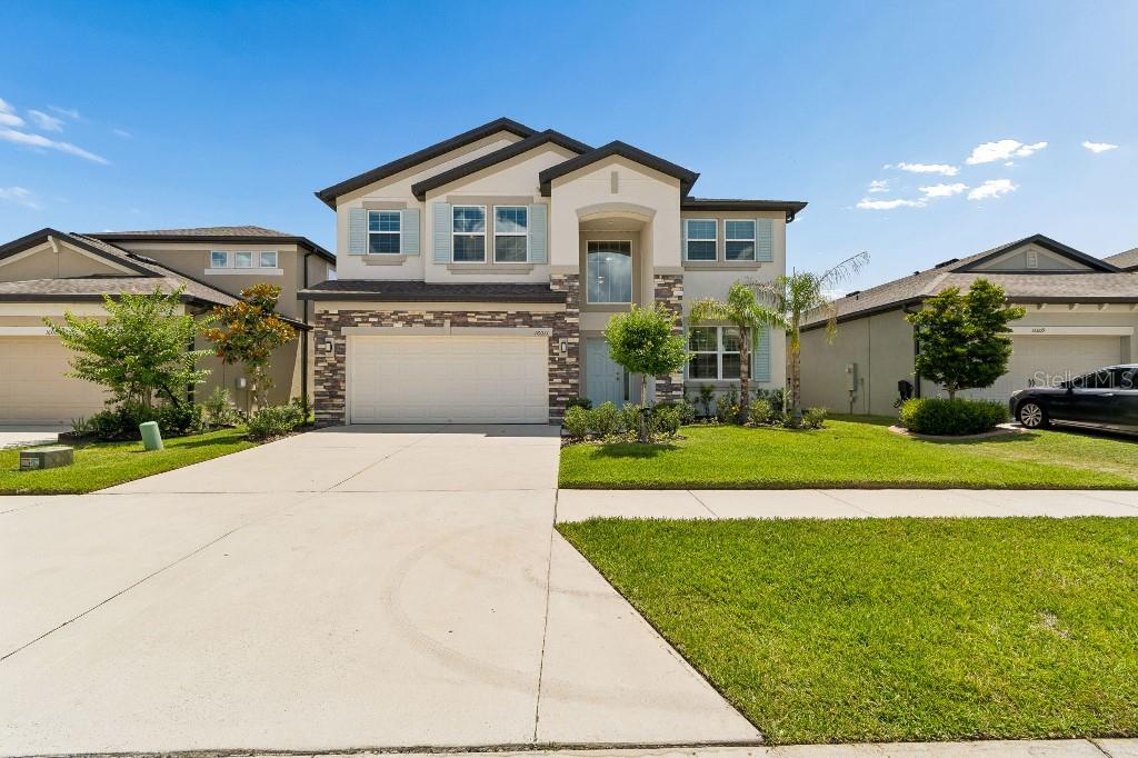 A two-story suburban house with a two-car garage, stone accents, and a manicured front lawn — 16011 SONOMA GROVE CIRCLE, TAMPA, FL