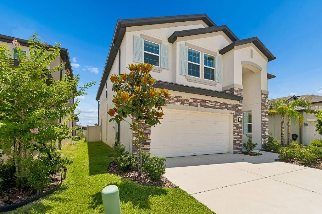 A two-story suburban house features a white stucco exterior, stone accents, and a two-car garage — 16011 SONOMA GROVE CIRCLE, TAMPA, FL