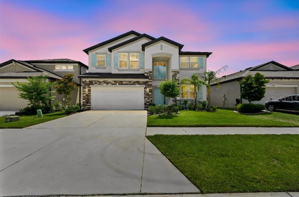 A two-story suburban house features a stone facade, a white garage, and a green lawn — 16011 SONOMA GROVE CIRCLE, TAMPA, FL