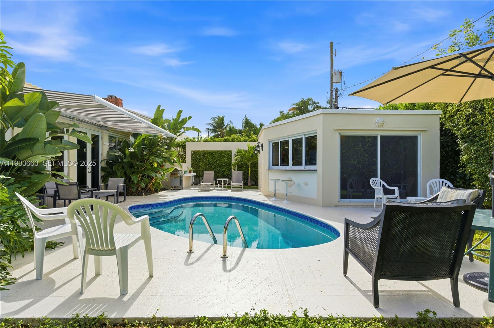 A backyard features a kidney-shaped swimming pool, patio furniture, and a detached pool house — 2607 Holy Cross Ln, Lake Worth FL 33460, LAKE WORTH, FL