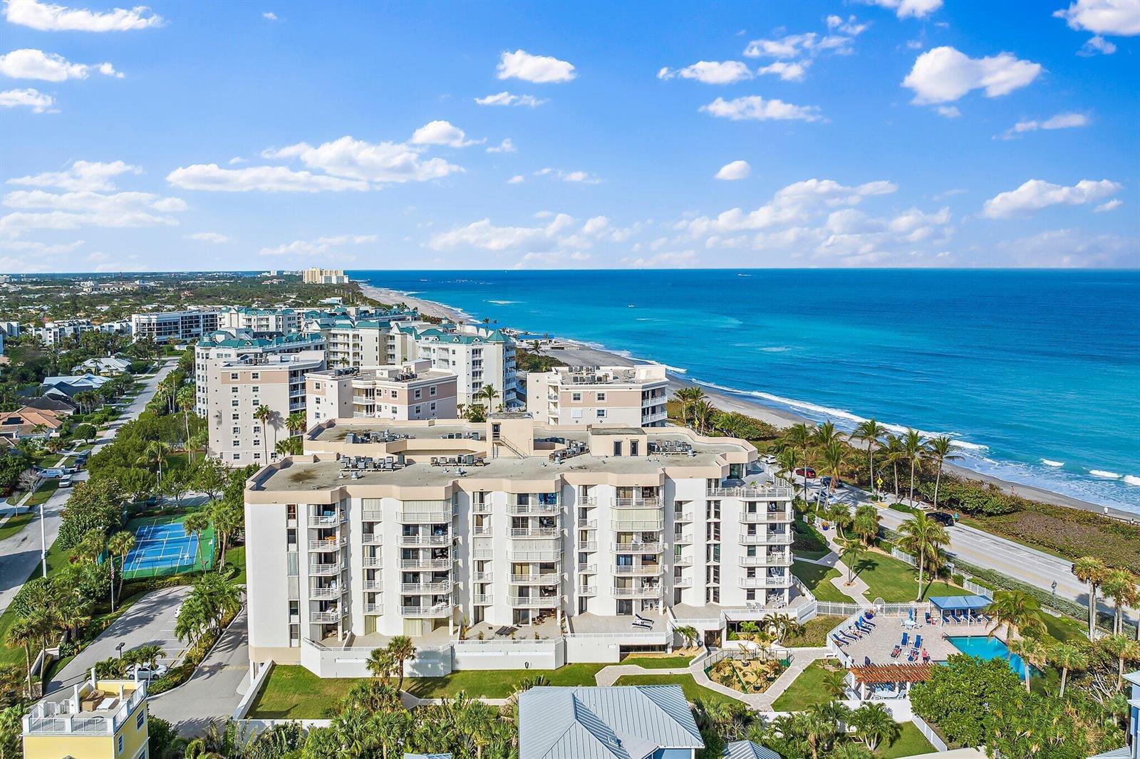 An aerial view of a multi-story beachfront condominium complex with a pool and tennis court — 176 Helios Drive # 606, Jupiter FL 33477, JUPITER, FL