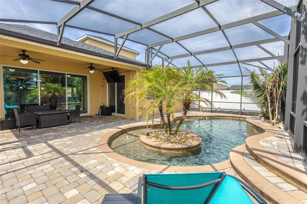 A screened-in patio features a paver deck, a swimming pool, and a central palm island — 4925 TORTOISE TRAIL, ST CLOUD, FL