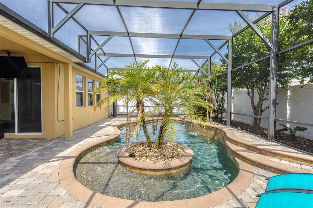 A screened-in patio features a swimming pool with a central island containing a palm tree — 4925 TORTOISE TRAIL, ST CLOUD, FL