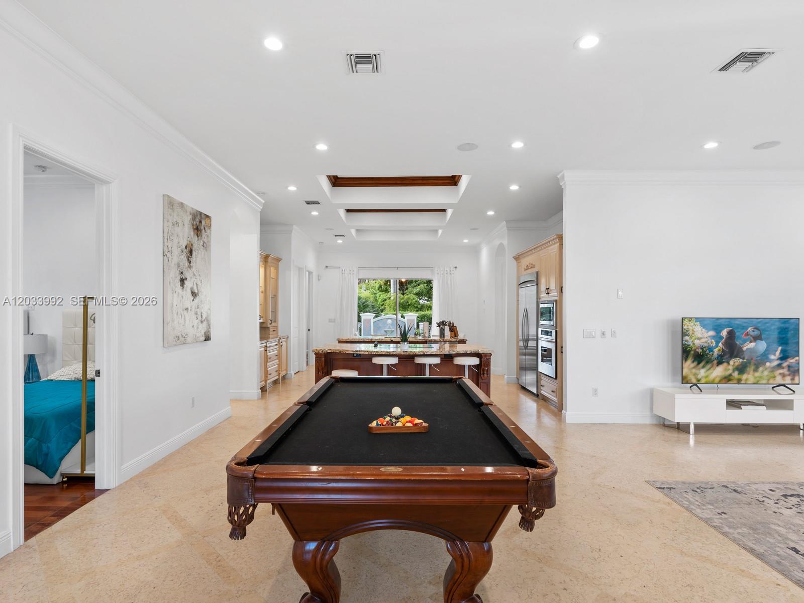 A spacious open-concept room features a pool table, a kitchen island, and a television — 1223 Jackson St, Hollywood FL 33019, HOLLYWOOD, FL