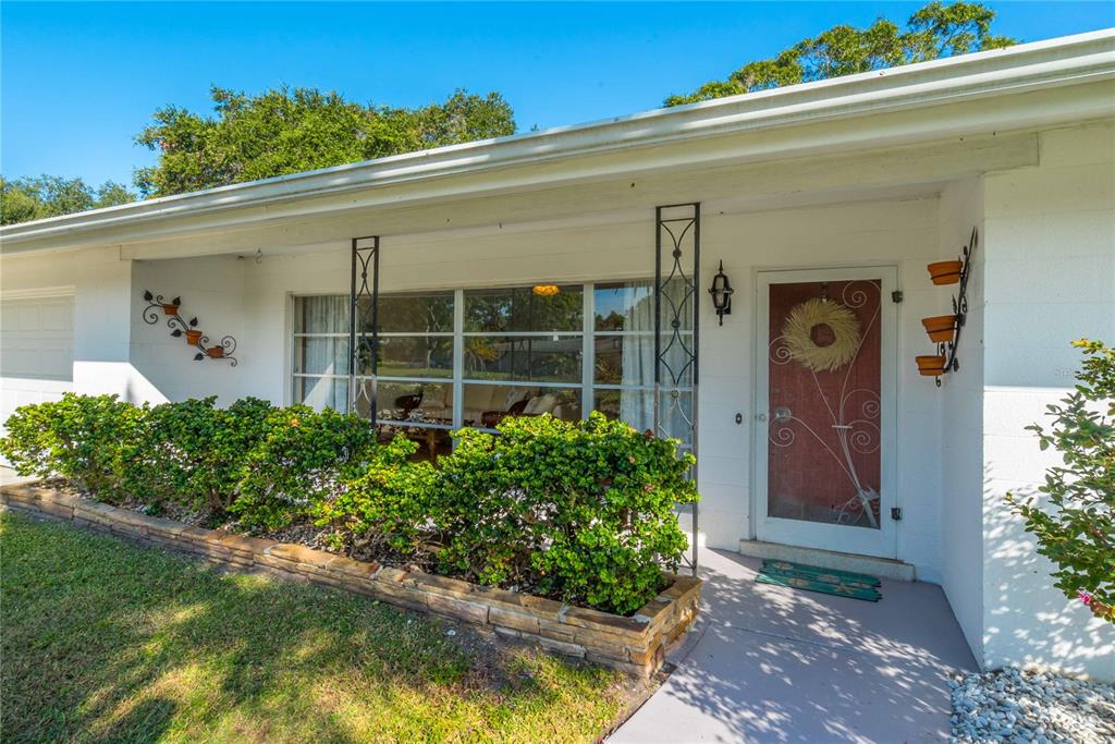 The exterior of a white house features a stone planter, metal porch columns, and a door — 2521 WEBBER STREET, SARASOTA, FL