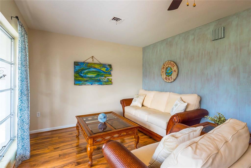 A living room features a beige sofa, a wooden coffee table, and beach-themed wall decor — 2521 WEBBER STREET, SARASOTA, FL