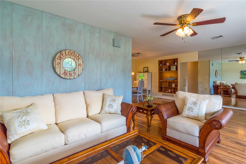 A living room features a light blue paneled wall, cream-colored furniture, and wood flooring — 2521 WEBBER STREET, SARASOTA, FL