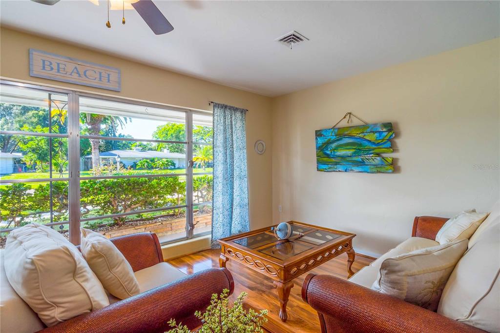 A living room features wicker furniture, a wooden coffee table, and a large window — 2521 WEBBER STREET, SARASOTA, FL