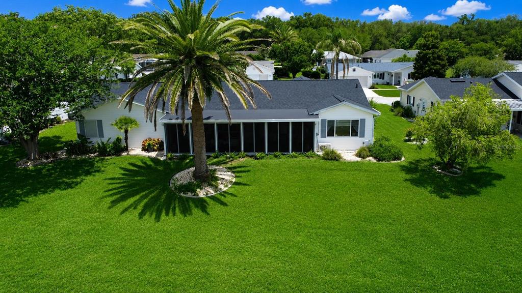 A sunroom with wood-look flooring features large glass windows overlooking a grassy golf course — 9900 SE 175TH PLACE, SUMMERFIELD, FL