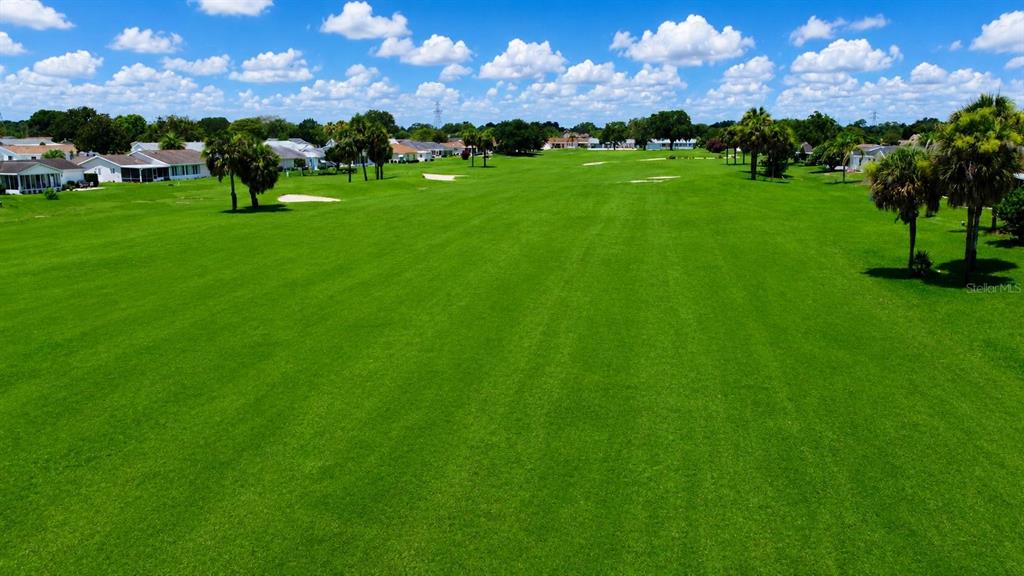 An elevated view of a golf course green with a pond and lighthouse in the background — 9900 SE 175TH PLACE, SUMMERFIELD, FL