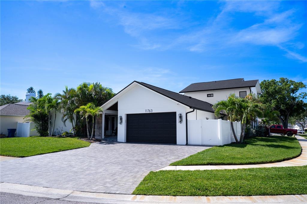 A white single-story house with a black garage door and a paved driveway — 11763 HARBORSIDE CIRCLE, LARGO, FL