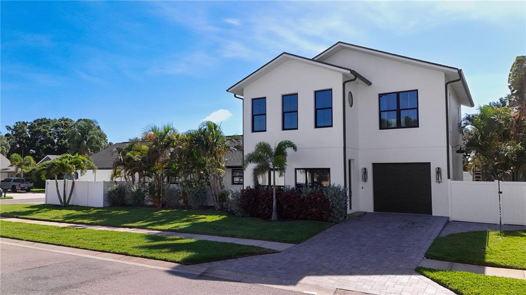 A two-story white house with a dark garage door and a paved driveway — 11763 HARBORSIDE CIRCLE, LARGO, FL