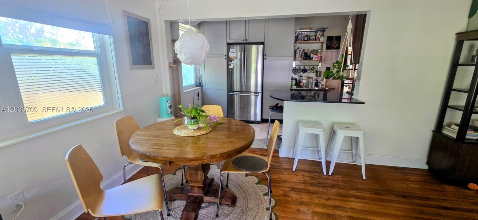 A dining area with a round wooden table sits adjacent to a kitchen with stainless appliances — 1135 NE 133 rd St, North Miami FL 33161, NORTH MIAMI, FL