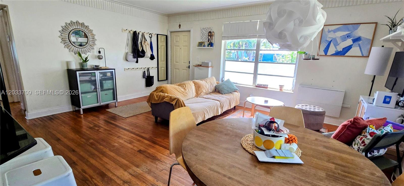 A living and dining area features hardwood floors, a beige sofa, and a round table — 1135 NE 133 rd St, North Miami FL 33161, NORTH MIAMI, FL