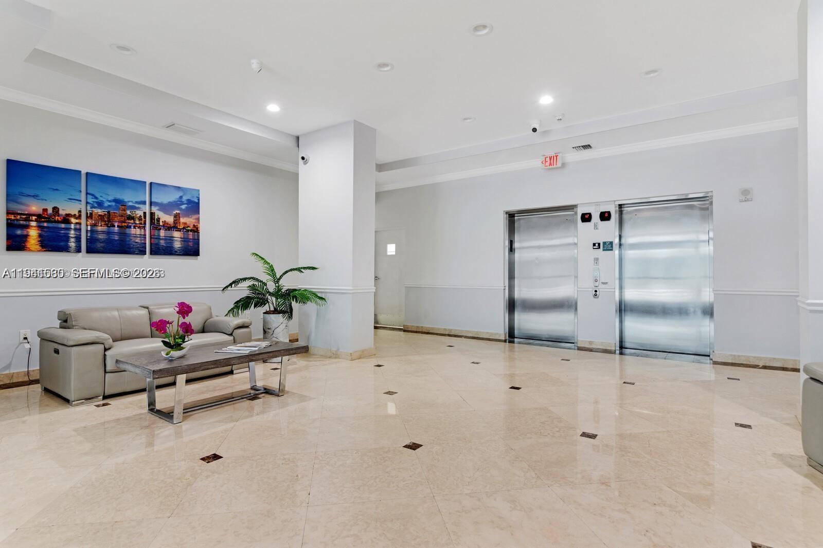 A lobby features a beige leather sofa, a coffee table, and two stainless steel elevators — 60 NW 37th Ave # 806, Miami FL 33125, MIAMI, FL