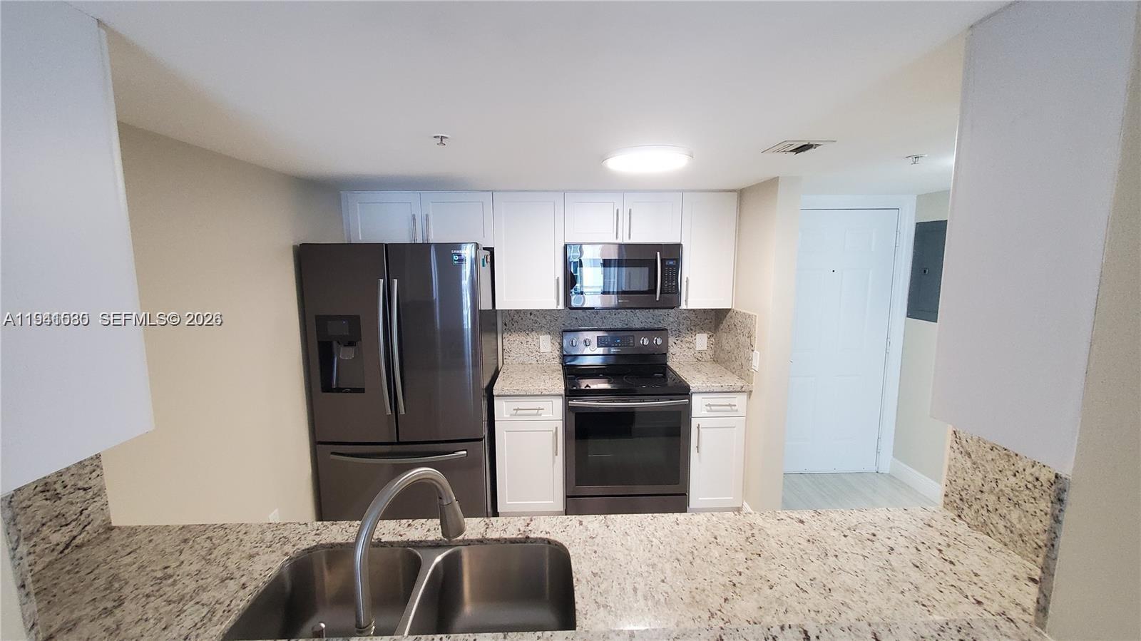 A kitchen features white cabinets, granite countertops, and stainless steel appliances — 60 NW 37th Ave # 806, Miami FL 33125, MIAMI, FL