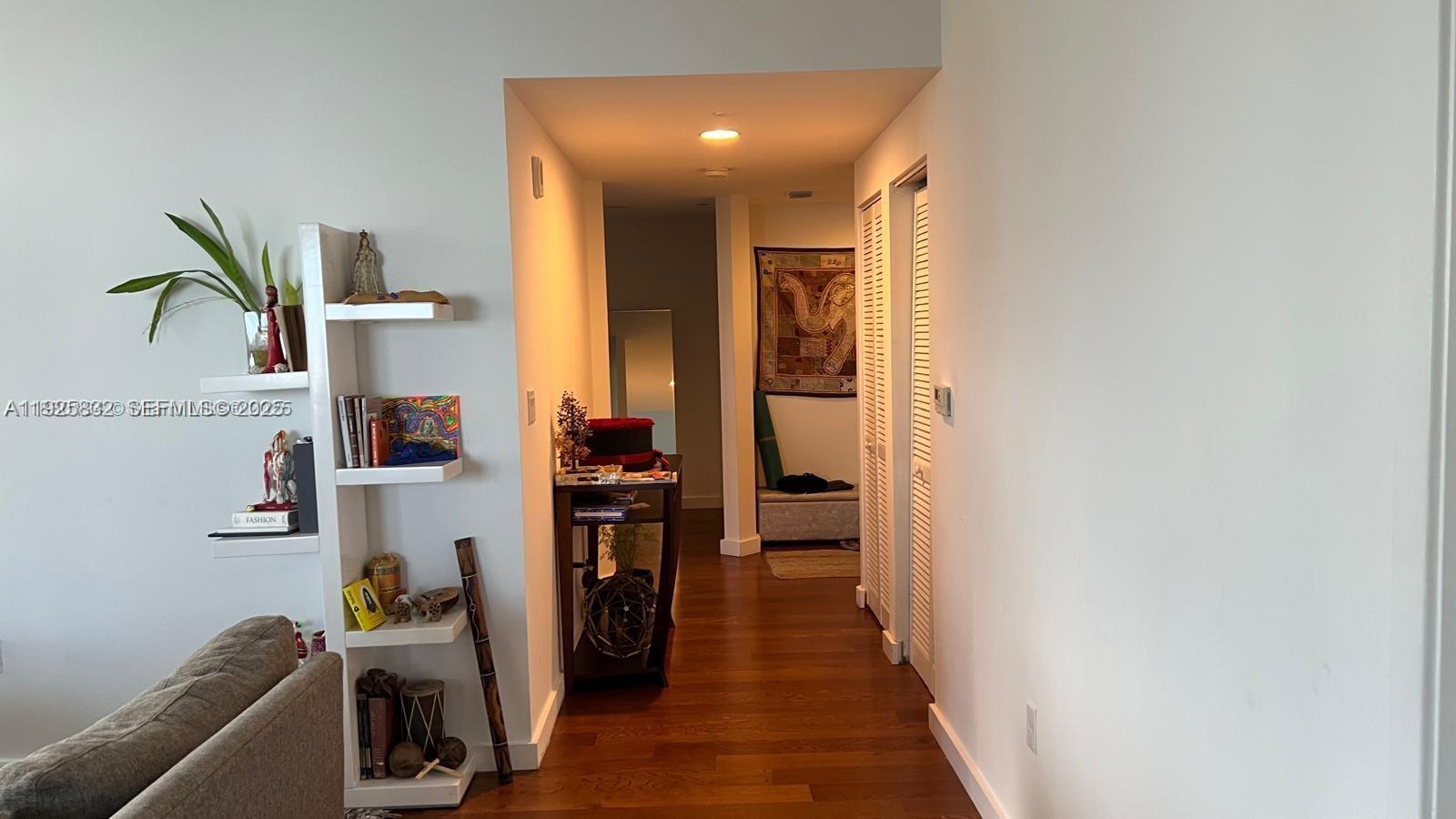 A hallway with hardwood floors leads past a white shelving unit toward a back room — 601 NE 23 ST # 1103, Miami FL 33137, MIAMI, FL