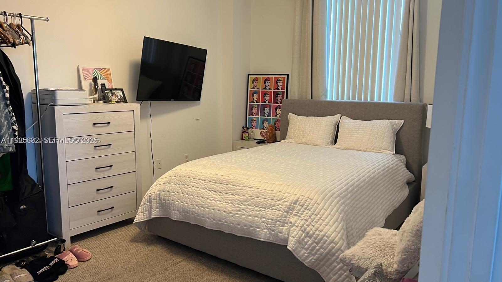 A bedroom features a gray upholstered bed, a white dresser, and a wall-mounted television — 601 NE 23 ST # 1103, Miami FL 33137, MIAMI, FL