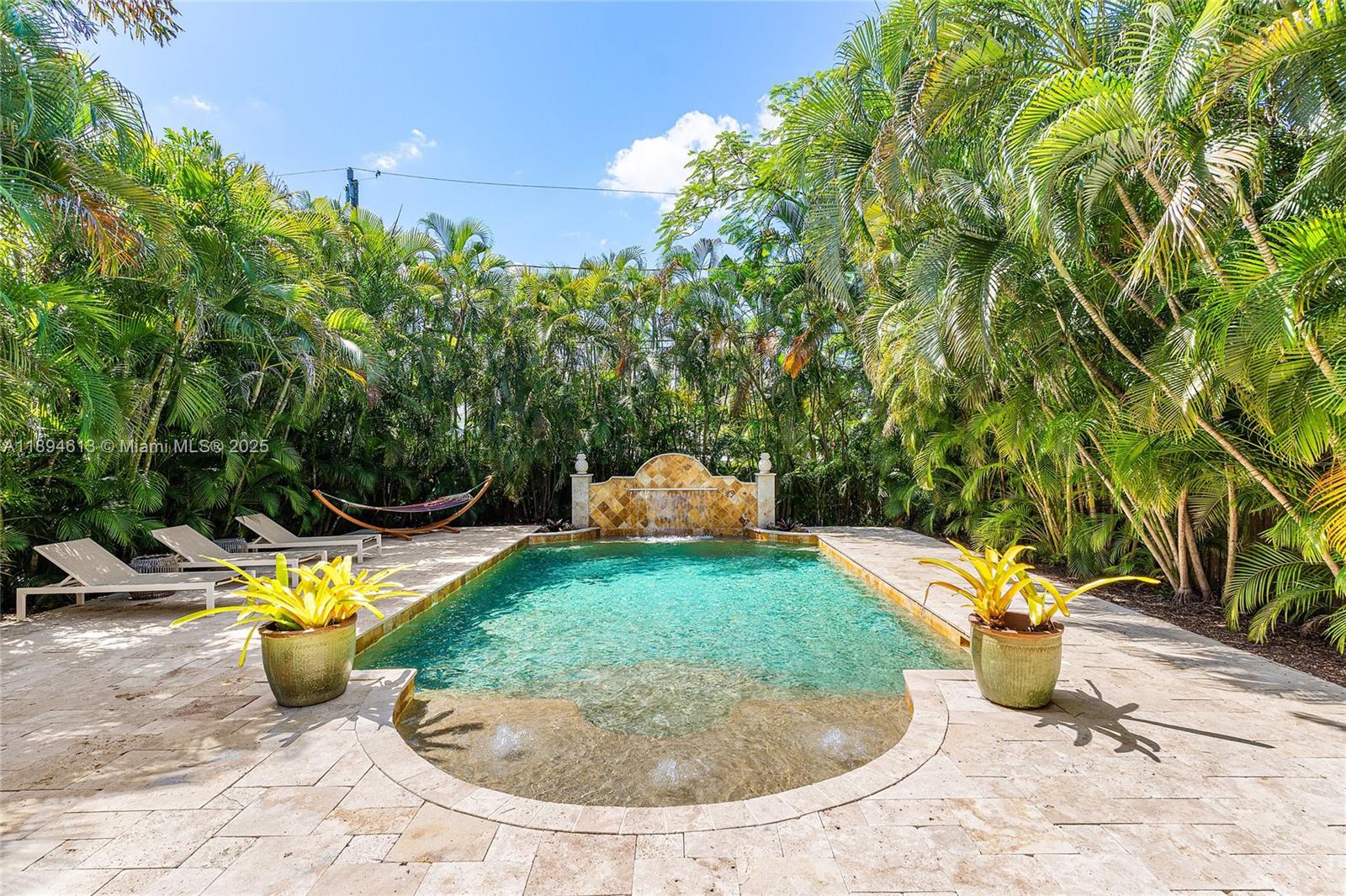 A rectangular swimming pool with a stone fountain and surrounding palm trees — 12 NE 26th St, Wilton Manors FL 33305, WILTON MANORS, FL