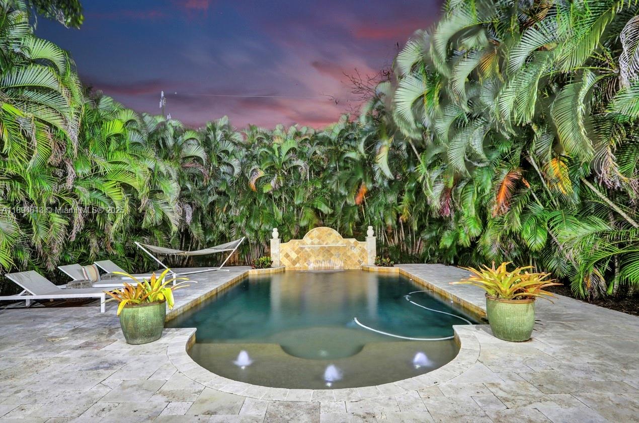 A rectangular swimming pool features a stone fountain, surrounding patio, and lush palm trees — 12 NE 26th St, Wilton Manors FL 33305, WILTON MANORS, FL