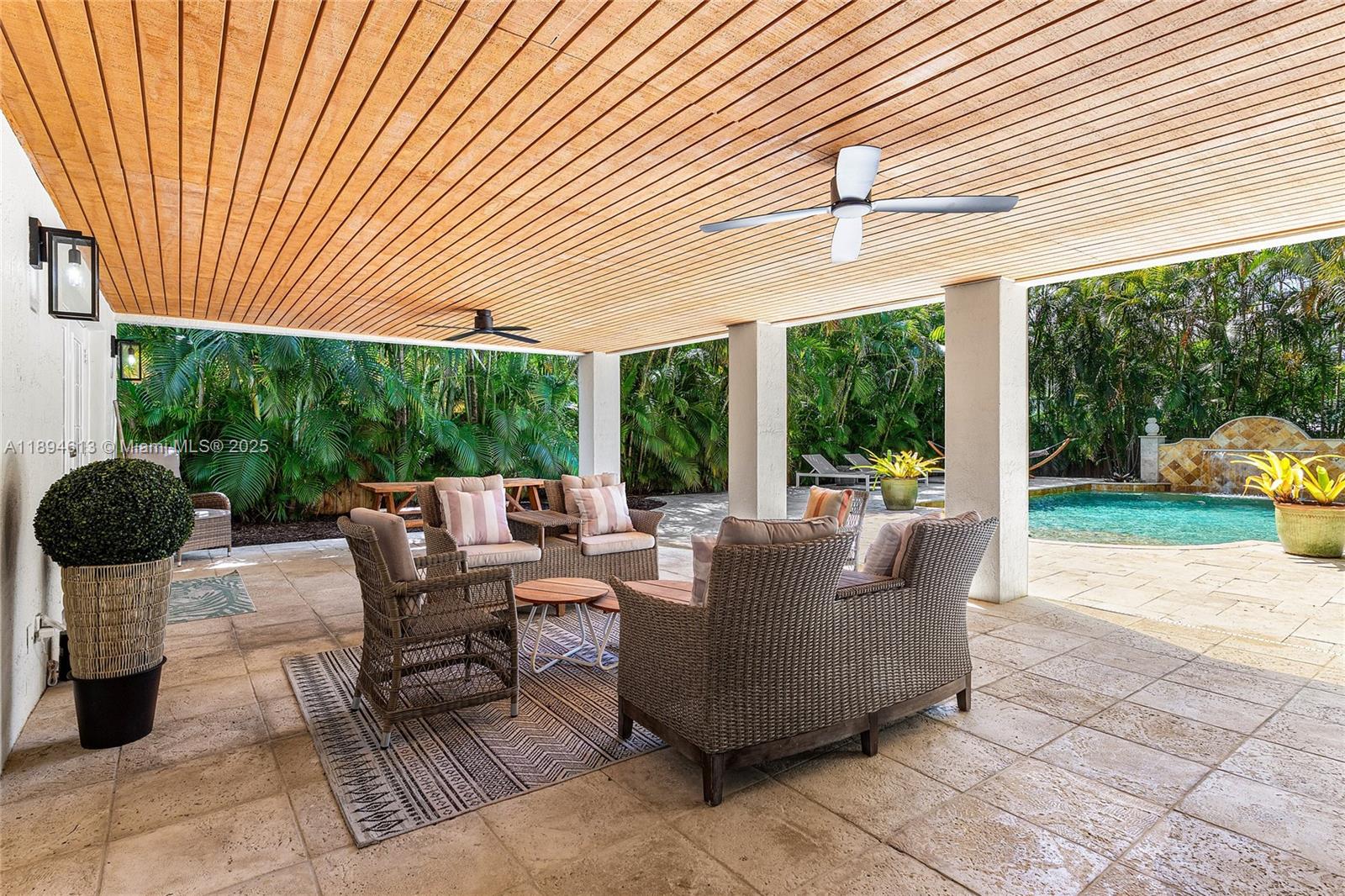 A covered outdoor patio features wicker furniture, a wood-paneled ceiling, and a swimming pool — 12 NE 26th St, Wilton Manors FL 33305, WILTON MANORS, FL