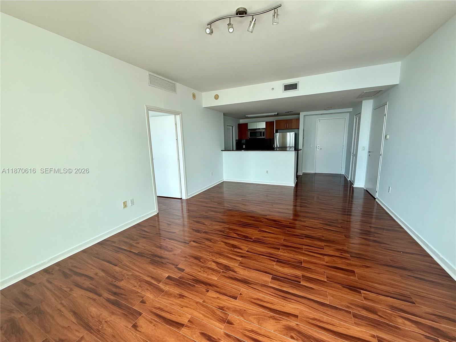 An open-concept living area features hardwood floors, a kitchen with dark cabinetry, and white walls — 300 S Biscayne Blvd # 3014, Miami FL 33131, MIAMI, FL
