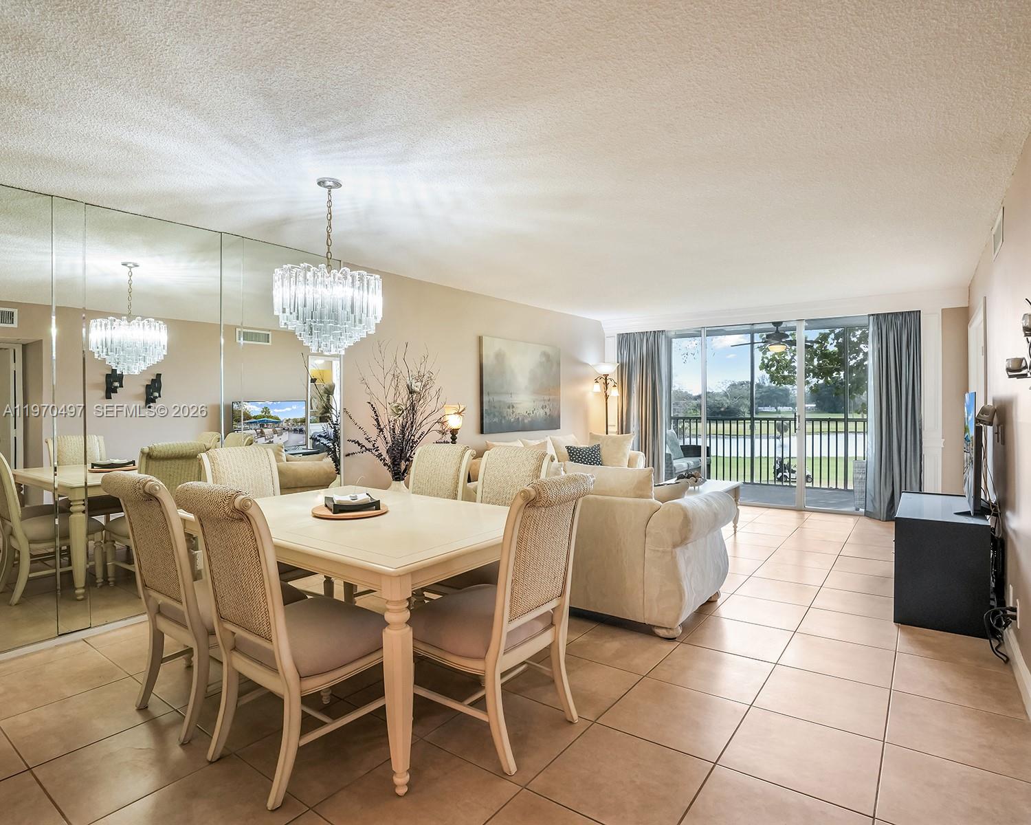 A dining area and living room feature tile floors, a crystal chandelier, and balcony views — 2681 S Course Dr # 209, Pompano Beach FL 33069, POMPANO BEACH, FL