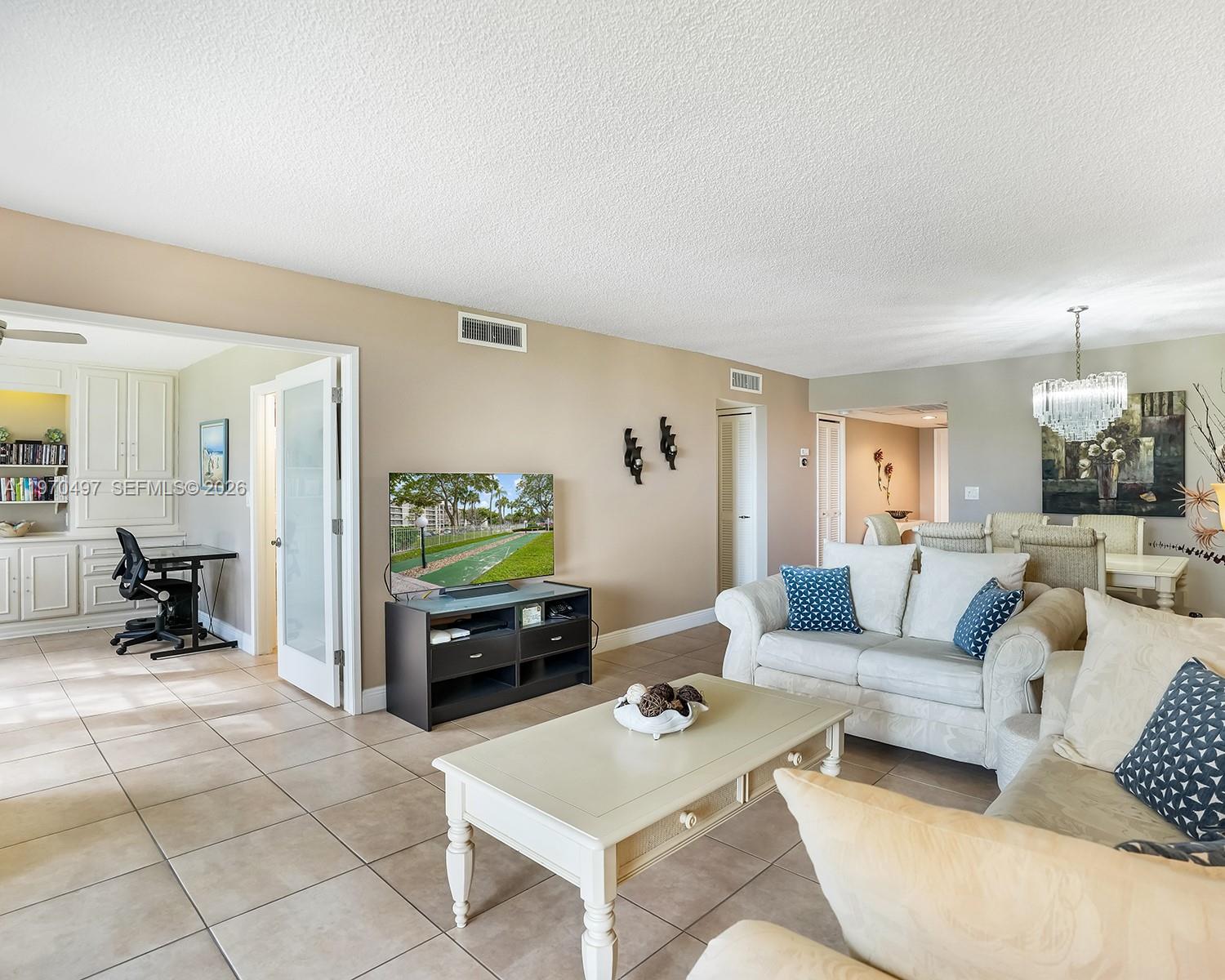 A living room features tile floors, a television on a stand, and adjacent office space — 2681 S Course Dr # 209, Pompano Beach FL 33069, POMPANO BEACH, FL