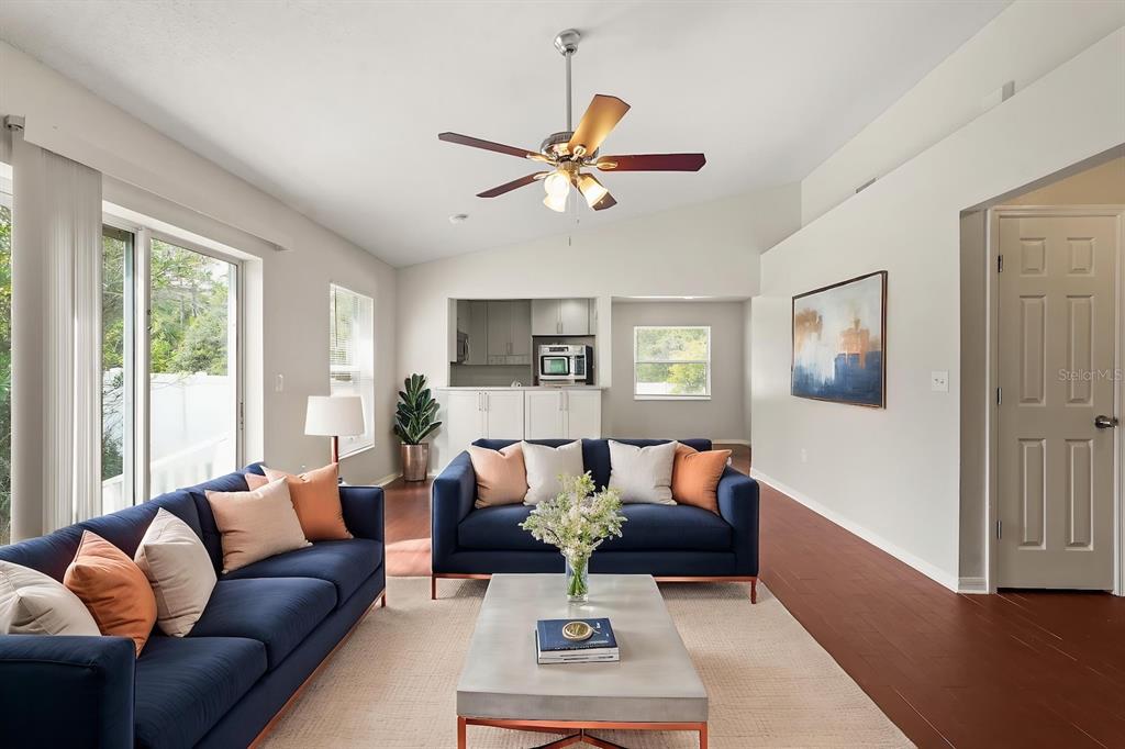 A living room features two navy blue sofas, a coffee table, and hardwood flooring — 525 PARTRIDGE DRIVE, KISSIMMEE, FL