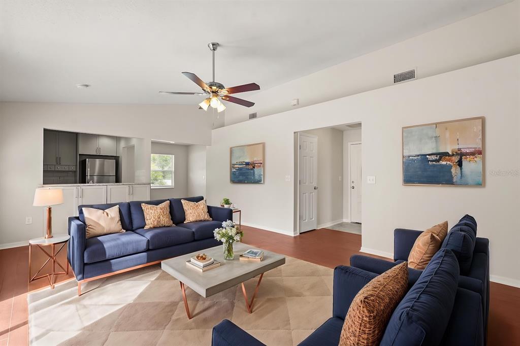A living room features a blue sofa, matching armchairs, a coffee table, and vaulted ceilings — 525 PARTRIDGE DRIVE, KISSIMMEE, FL
