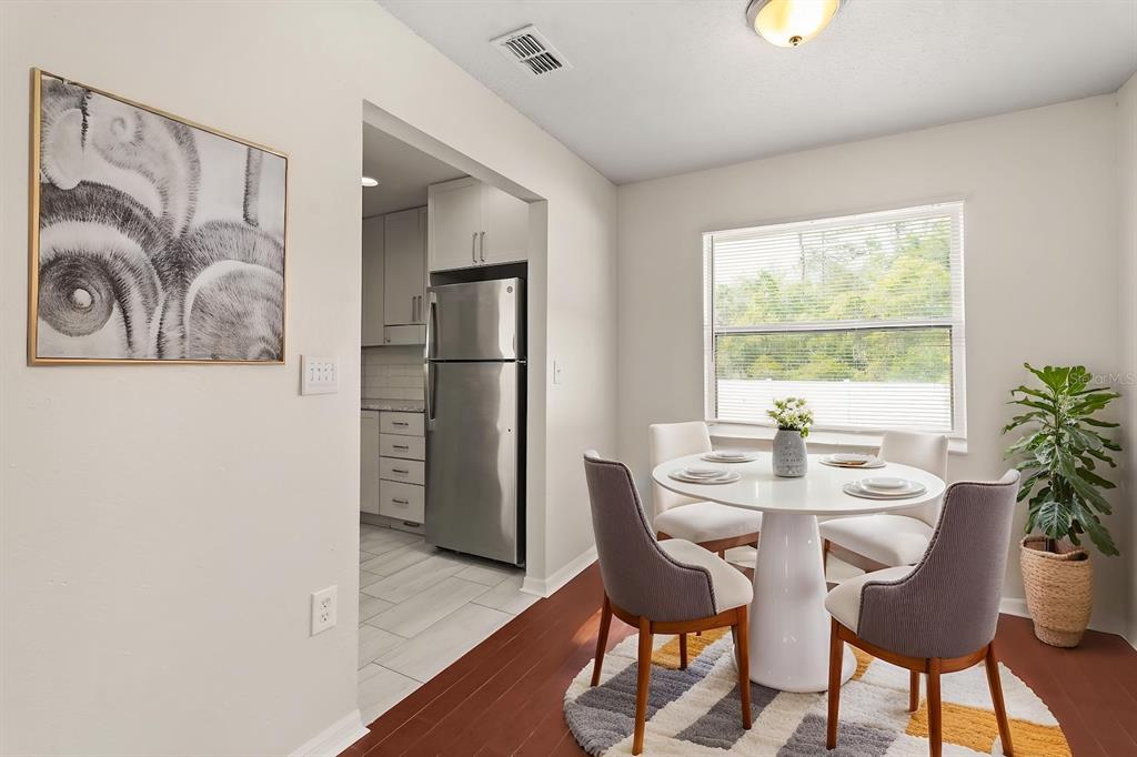 A dining area with a round white table, four chairs, and a view into the kitchen — 525 PARTRIDGE DRIVE, KISSIMMEE, FL