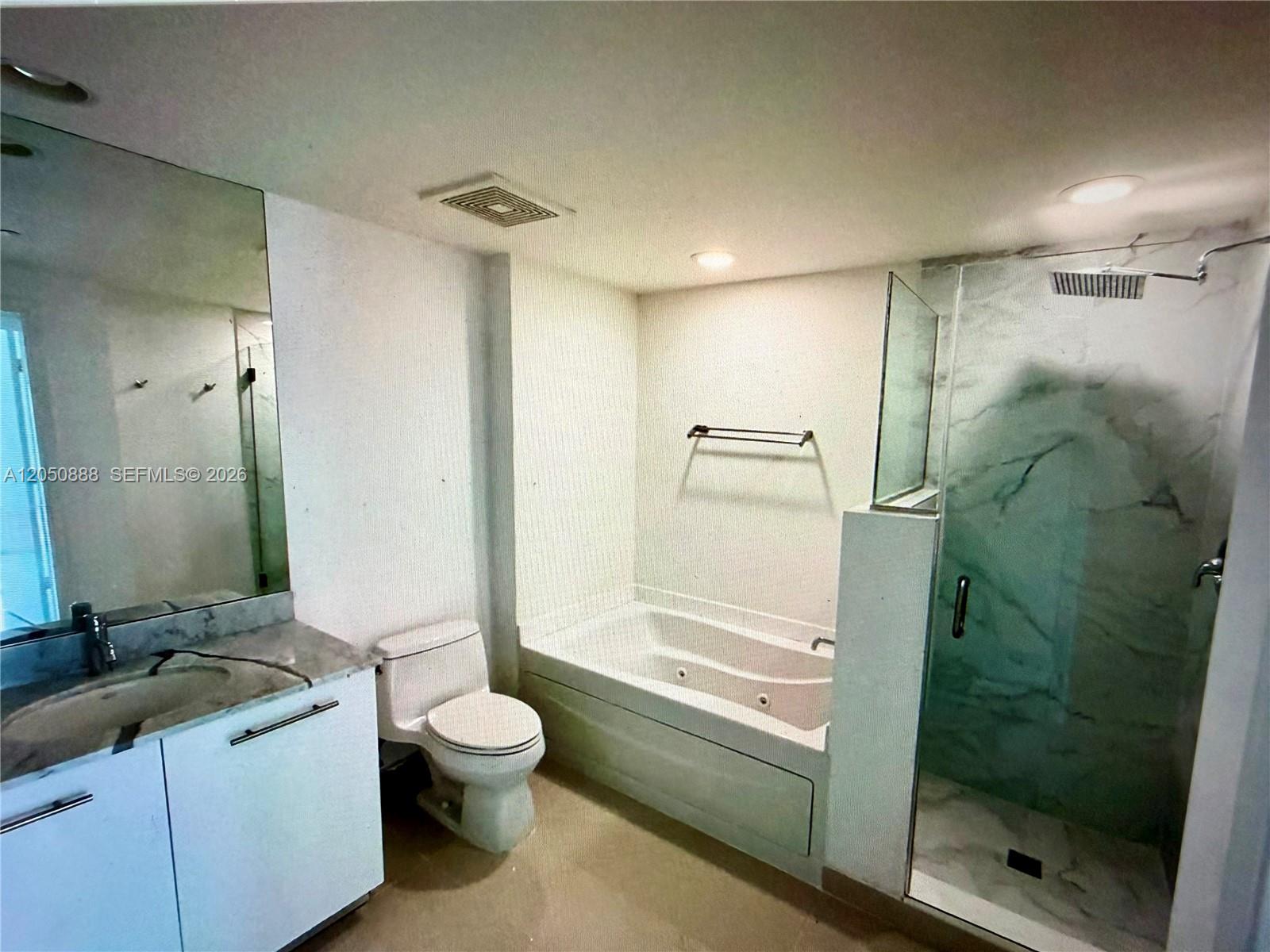 A bathroom features a vanity, toilet, soaking tub, and a glass-enclosed walk-in shower — 500 Brickell Ave # 2003, Miami FL 33131, MIAMI, FL