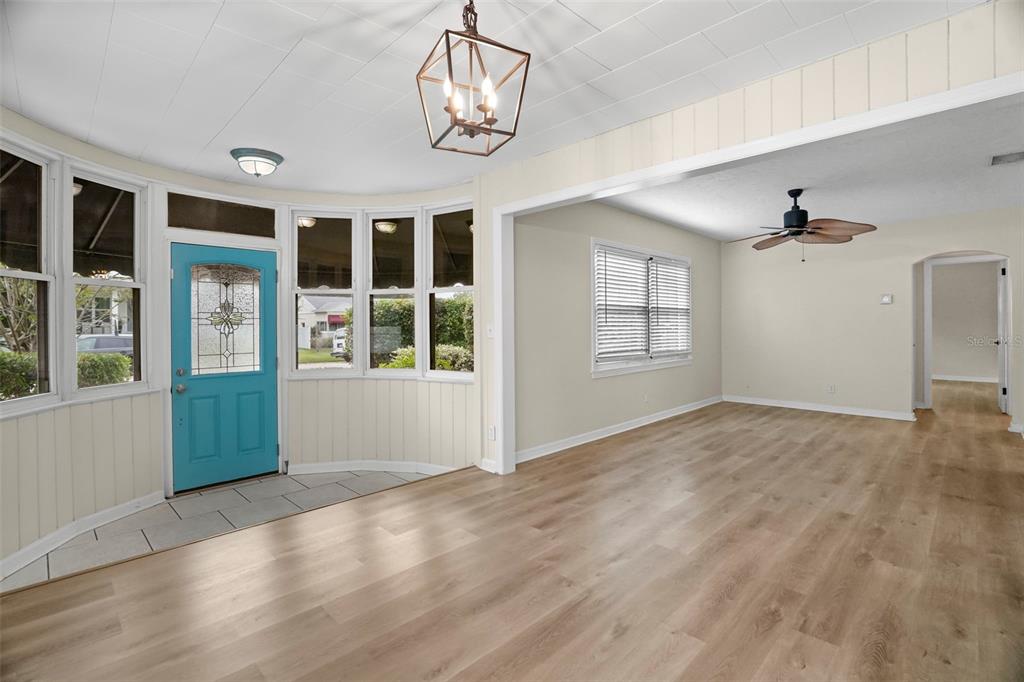 A bright living area features light wood flooring, a teal front door, and a chandelier — 446 37TH AVENUE NE, ST PETERSBURG, FL