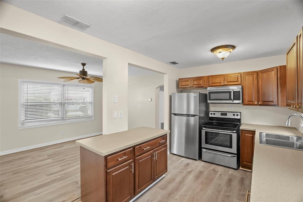 A kitchen with wood cabinets, stainless steel appliances, and a peninsula overlooking a dining area — 446 37TH AVENUE NE, ST PETERSBURG, FL