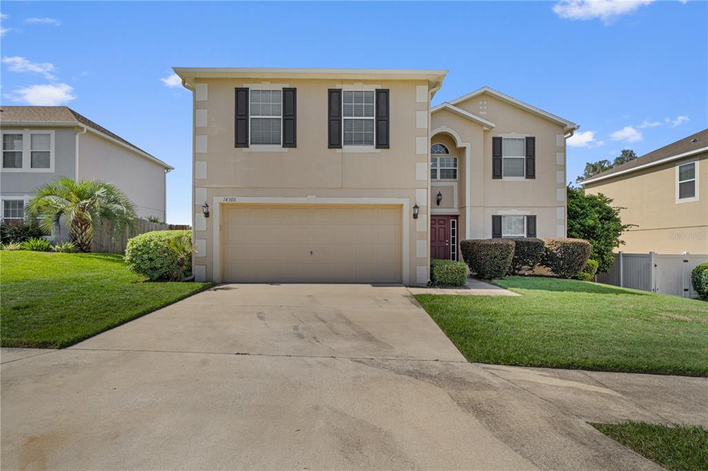 A two-story house with a beige exterior, a two-car garage, and a front lawn — 14308 NW 161ST AVENUE, ALACHUA, FL