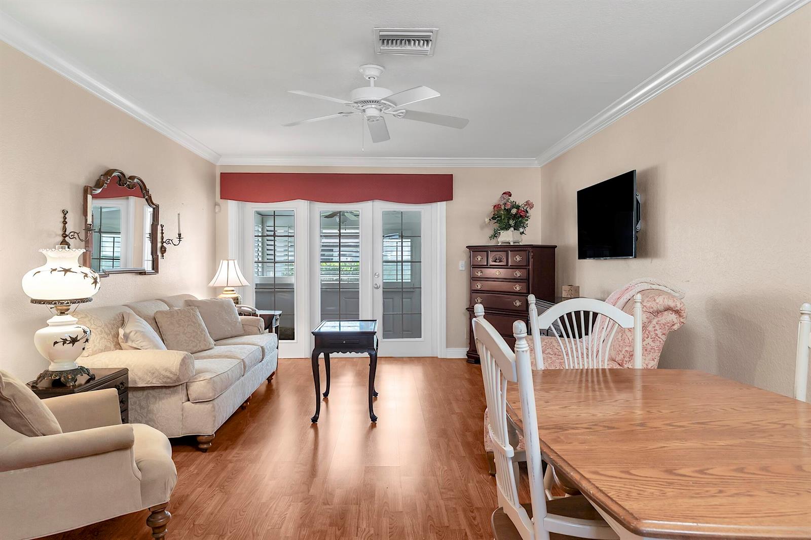 A living and dining area features wood-look flooring, a ceiling fan, and glass patio doors — 2930 Crosley Drive E # M, West Palm Beach FL 33415, WEST PALM BEACH, FL