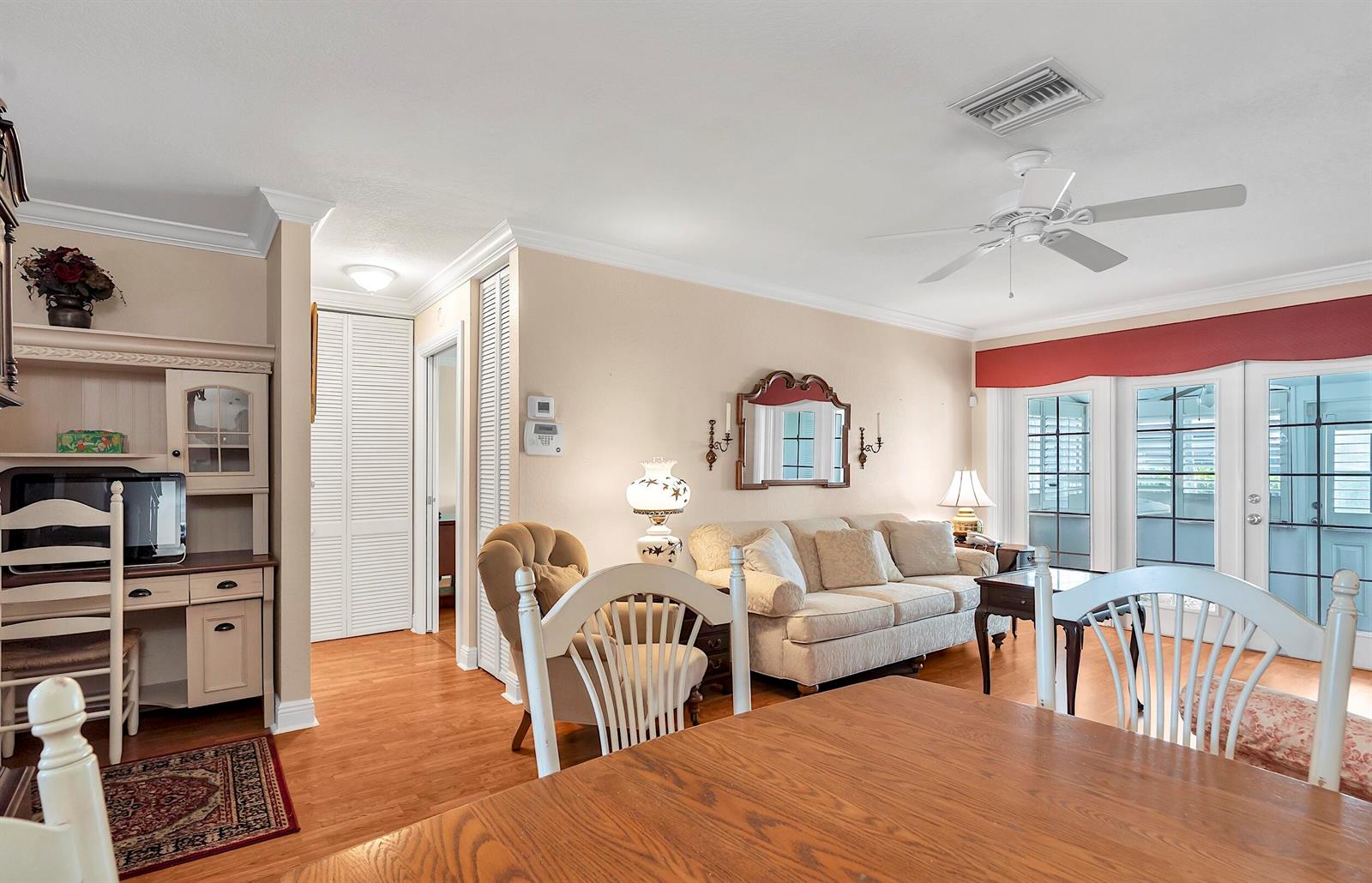 A living room features a beige sofa, a wooden desk, and a dining table — 2930 Crosley Drive E # M, West Palm Beach FL 33415, WEST PALM BEACH, FL